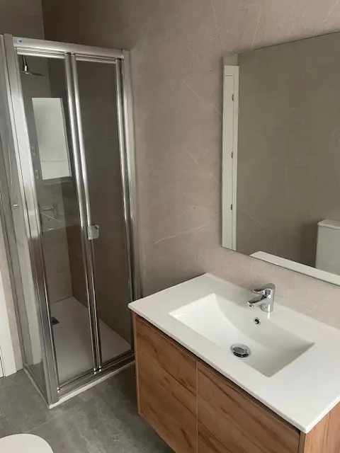 Baño completo reformado con plato de ducha, mampara y mueble de baño en Granada
